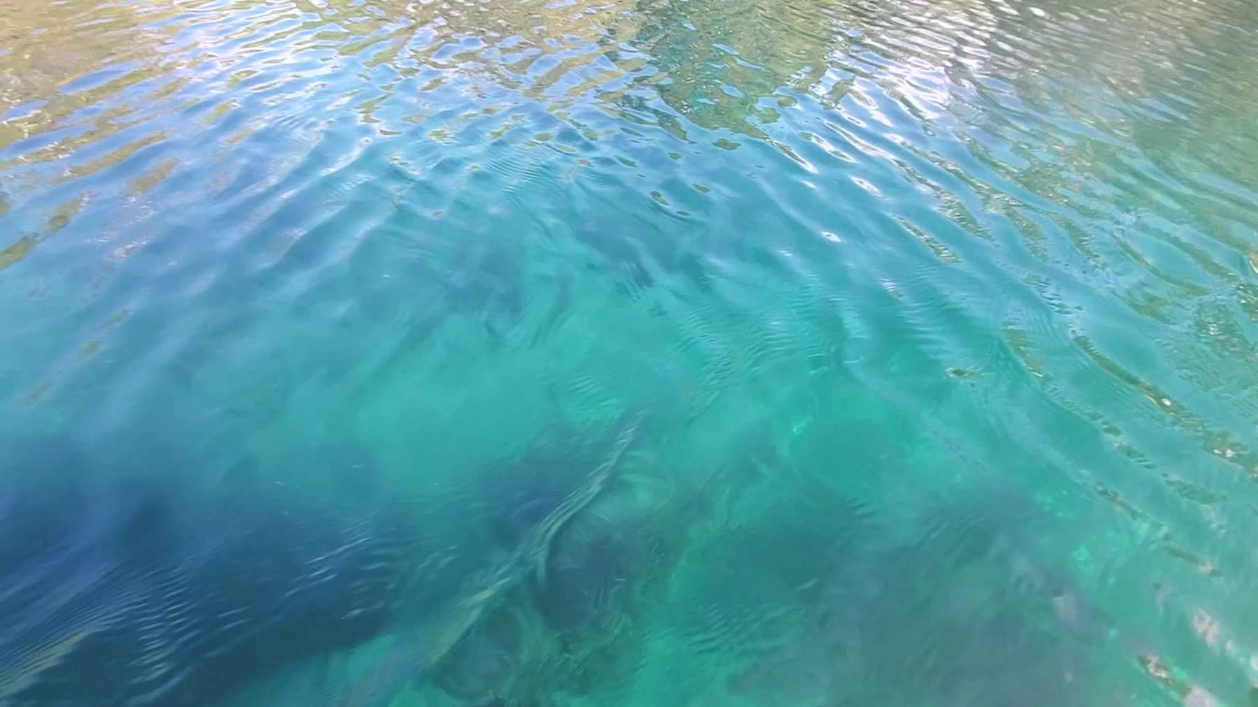 Sunlit turquoise water rippling over a sandy bottom